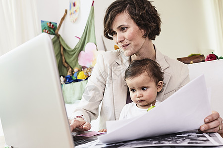 母亲与女婴同坐在笔记本电脑前工作图片