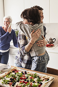 母亲和儿子在厨房里高兴拥抱图片