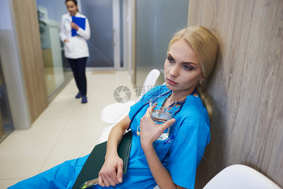 外科医生坐在走廊里举着水拿着病历本沉思图片