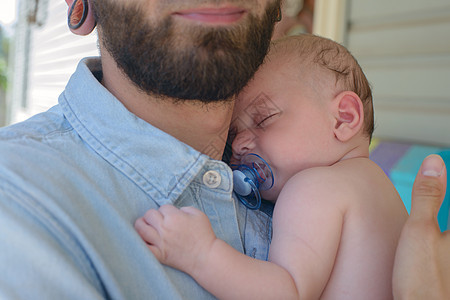 睡着的婴儿男孩靠在父亲肩上图片