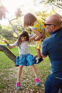 父亲和女儿在户外玩耍女儿坐在树上图片