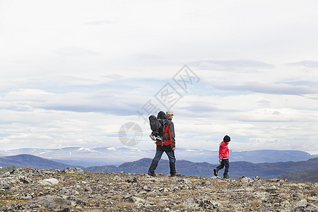 挪威奥普兰州洛美公园山地上背着一个小孩的男人走在儿子后面图片