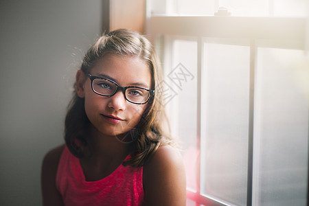 年轻女孩戴眼镜站在窗边图片