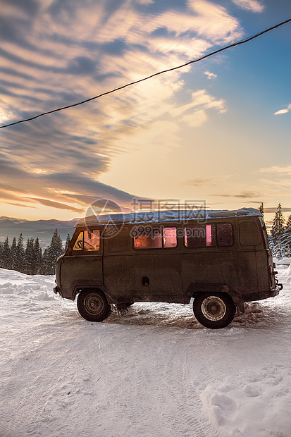 日落时被雪覆盖的野营车图片