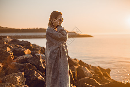 戴太阳眼镜的妇女站在海边图片