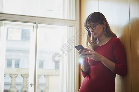 在办公室看智能手机的女商人图片