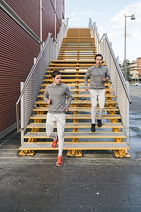 年轻男双胞胎一起跑下城市楼梯图片