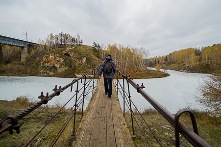 在俄罗斯埃文克河吊脚桥上行走年轻男子图片