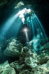 墨西哥金塔纳罗奥州图卢姆市有阳光和岩石层的地下河流注中男潜水员图片