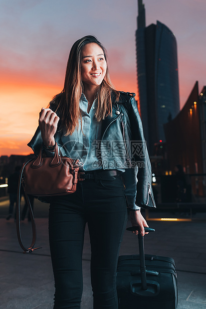 女商人走在户外拉着轮式手提箱图片