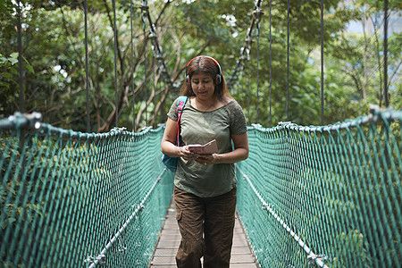 马来西亚吉隆坡森林生态公园桥上低头看手机的旅游者图片