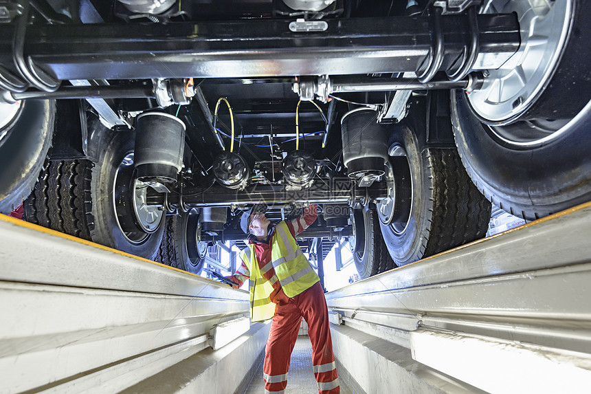 在拖车厂生产线上检查拖车底部的工人