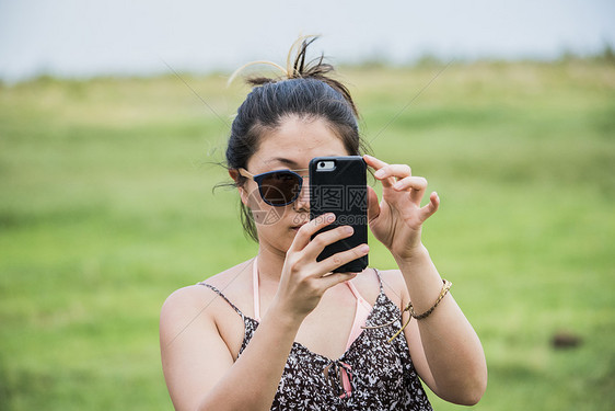 用智能手机拍摄照片的年轻女游客图片