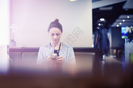 坐在机场休息室使用手机的女性图片