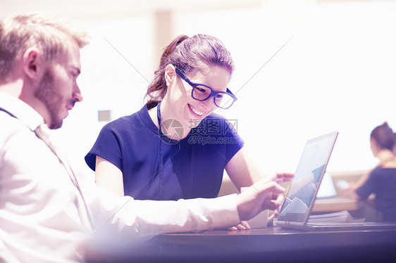 在机场休息室使用笔记本电脑讨论工作的商人和妇女图片