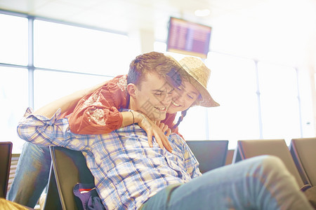 女人伸手拥抱坐在机场座位的年轻男子图片