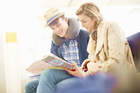 坐在机场出发休息室的年轻夫妇看旅行规划的低角度视图图片