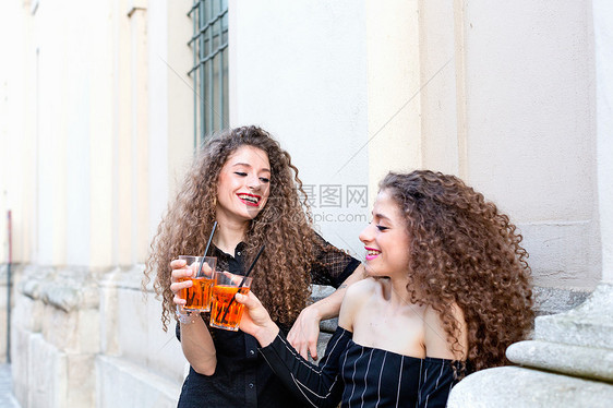 穿着时髦的双胞胎姐妹在喝鸡尾酒图片