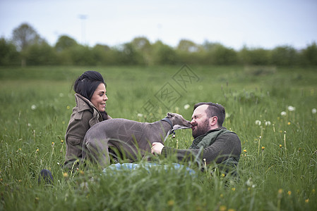 躺在田野中和狗玩闹的夫妻图片