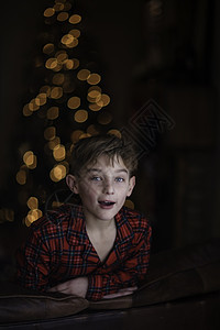 在圣诞树背景下靠着沙发的男孩图片