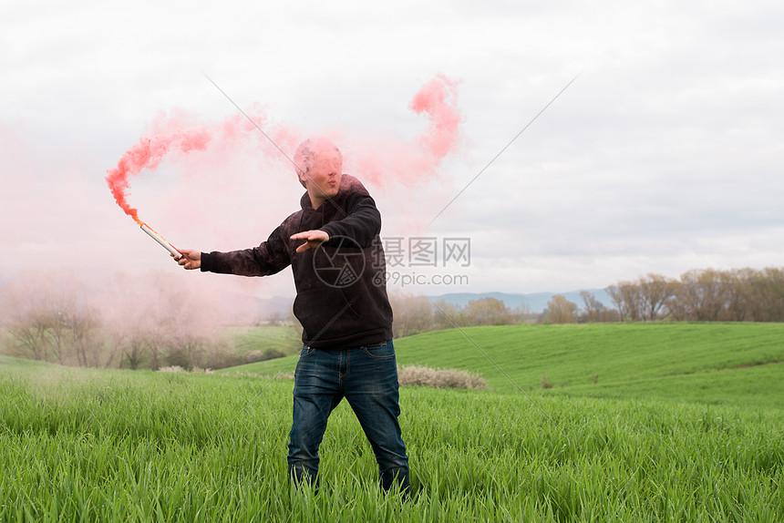 站在草地上挥舞着烟雾弹的男人图片