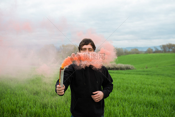 站在草地上拿着着烟雾弹的男人图片