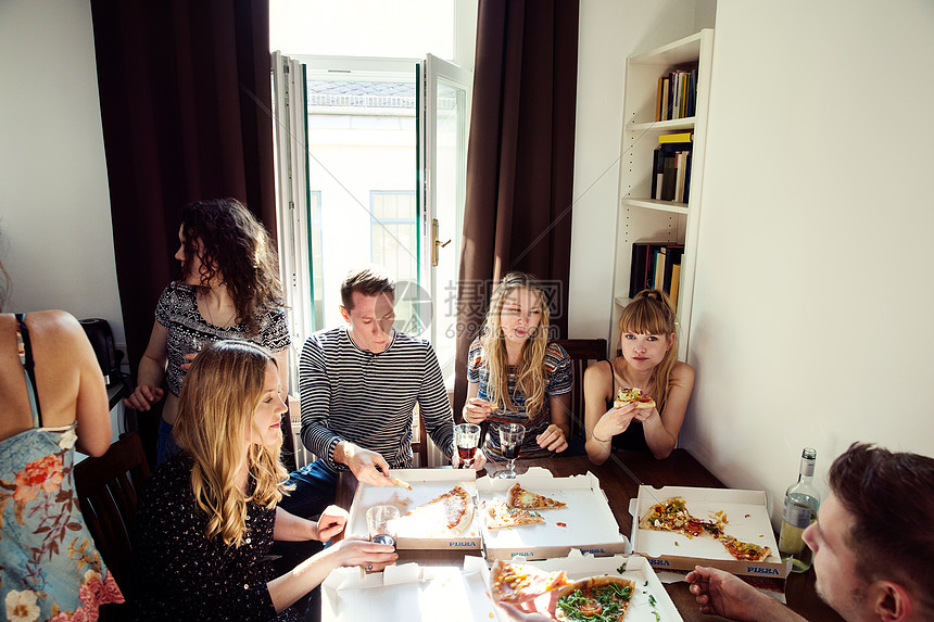 一群朋友在家里聊天喝酒吃比萨饼图片