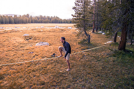 美国加利福尼亚州约塞米蒂公园草甸上一名年轻人在松弛线上练习平衡图片