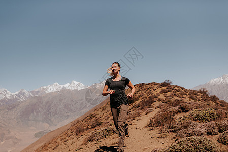 妇女从山顶上慢跑下来AnnapurnaCircular喜马拉雅山Muktinath尼泊尔图片