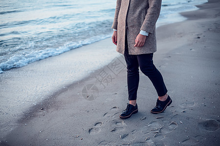 年轻妇女在海滩上行走留下脚印在湿沙低地段的中图片