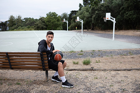 男青少年篮球运动员坐在场的公园长椅上图片