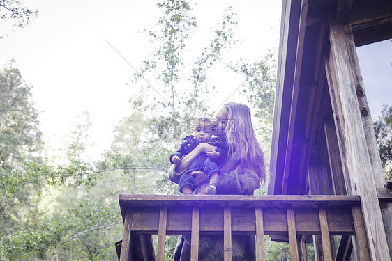 美国加利福尼亚州卡扎德罗市森林木屋阳台上抱着儿子亲吻的母亲图片