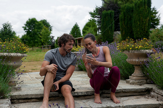 男人和女在花园里做瑜伽看着院子里的智能手机图片