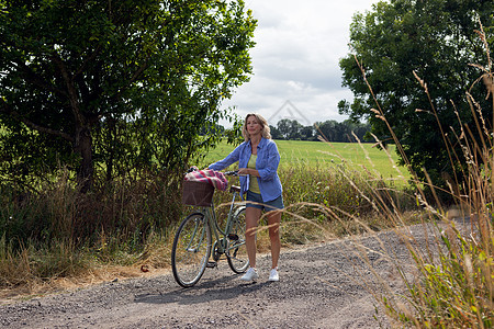 在农村公路沿途推自行车的孕妇图片