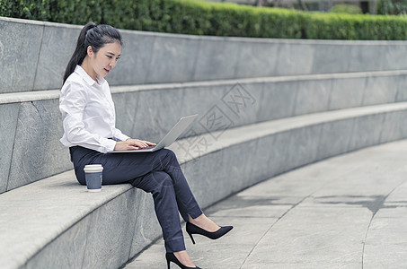 在上海市室外的台阶上打笔记本电脑的年轻女商人图片