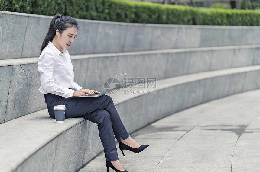 在上海市室外的台阶上打笔记本电脑的年轻女商人图片