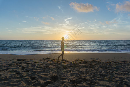 日落时在海滩上行走的人图片