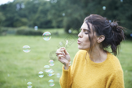 在野外玩肥皂泡的妇女图片