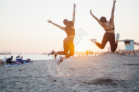 朋友在美国加利福尼亚州长海滩上跳跃背影图片