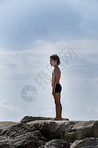 站在海滩岩石上的男孩图片