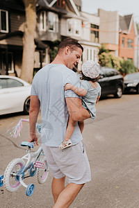 街头抱着女儿的男人拎着儿童车背景图片