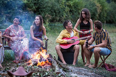 年轻人在公园的营火派对上弹吉他唱歌图片