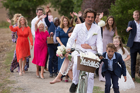 婚礼客人在挥手新婚夫妇在骑自行车图片