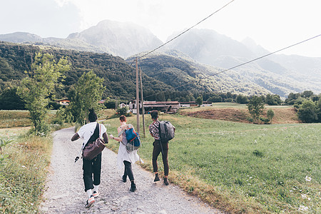 三个年轻的朋友沿泥土道徒步旅行的背影特伦蒂诺阿尔托迪意大利图片