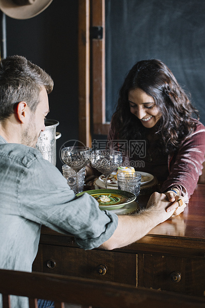 年轻夫妇面对面吃饭时手牵手图片