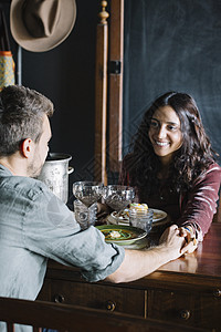 两人晚餐年轻夫妇面对面吃饭时手牵手背景