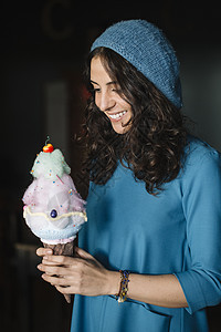 带着着蓝毛线帽拿着大冰淇淋甜筒的女子在微笑图片
