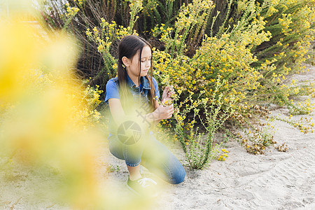 女孩跪在地上看着植物上图片