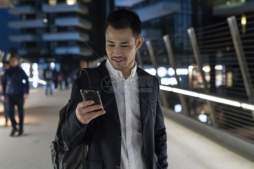 年轻商人晚上在街上看手机走路意大利米兰图片