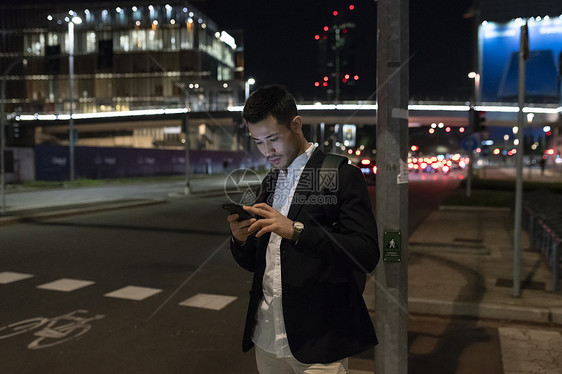 夜晚在街上的年轻商人看着手机意大利米兰图片